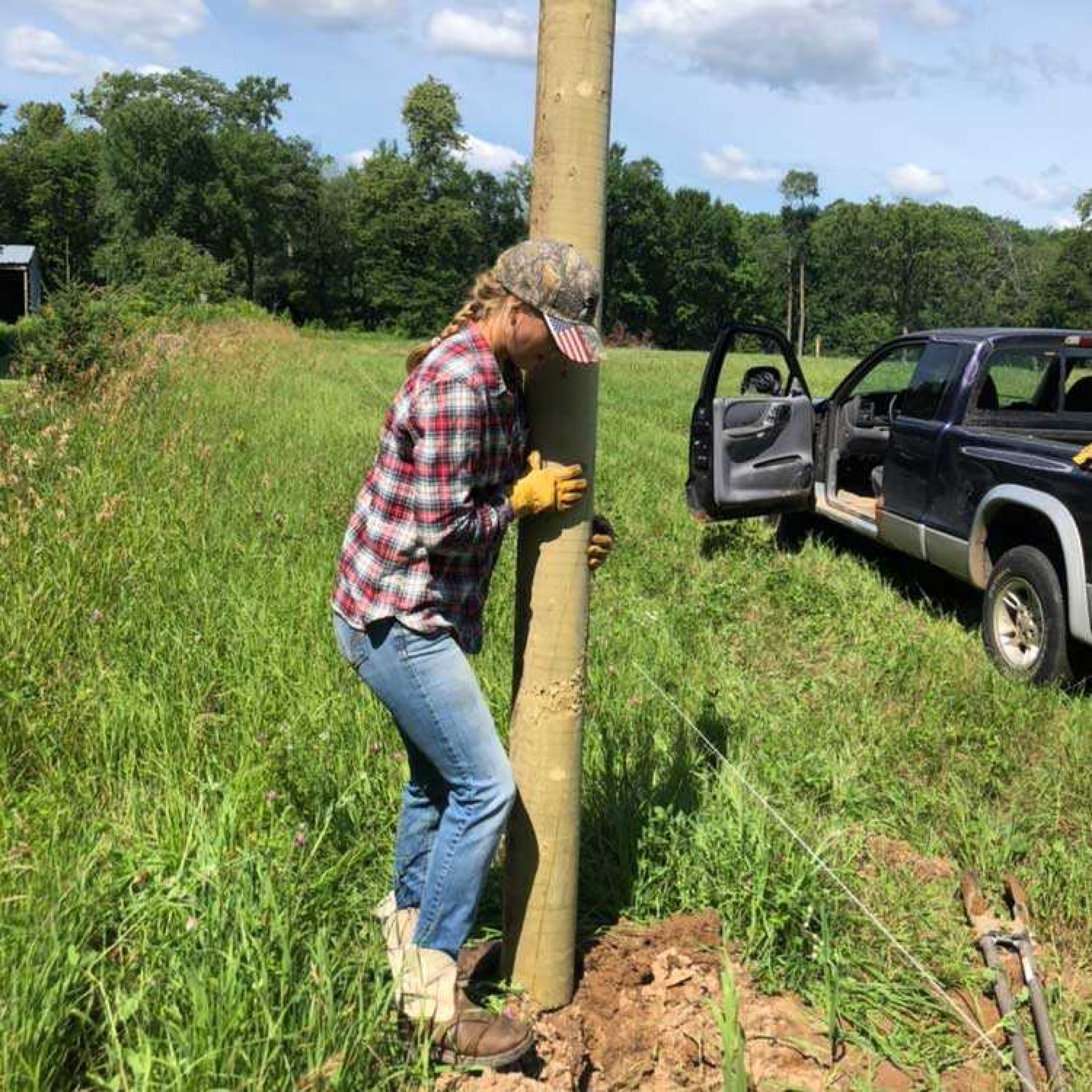 Young woman installing fence posts